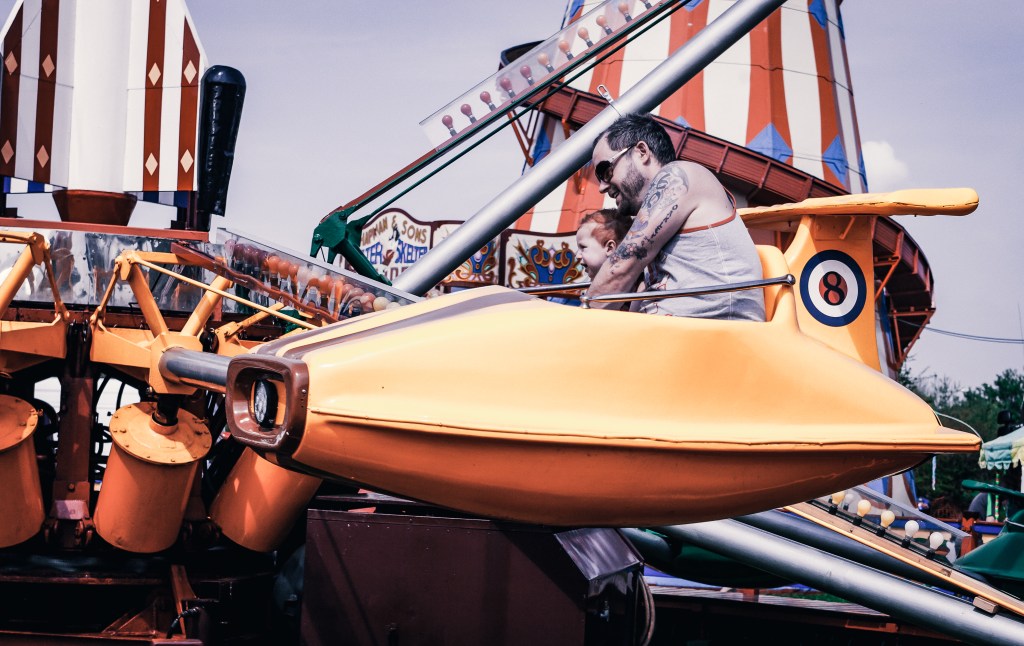 Dad and son on a carnival ride together.